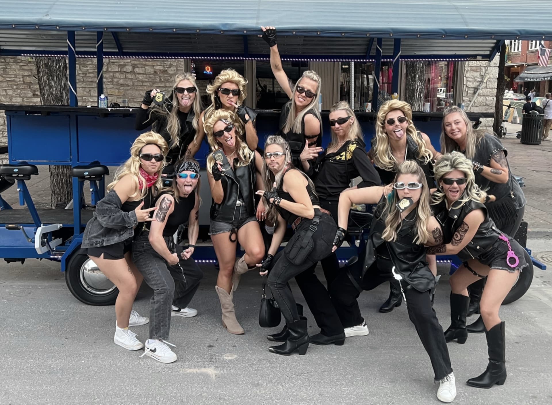 Bachelorette party group of 12 posing with BYOB party bike on 6th Street Austin